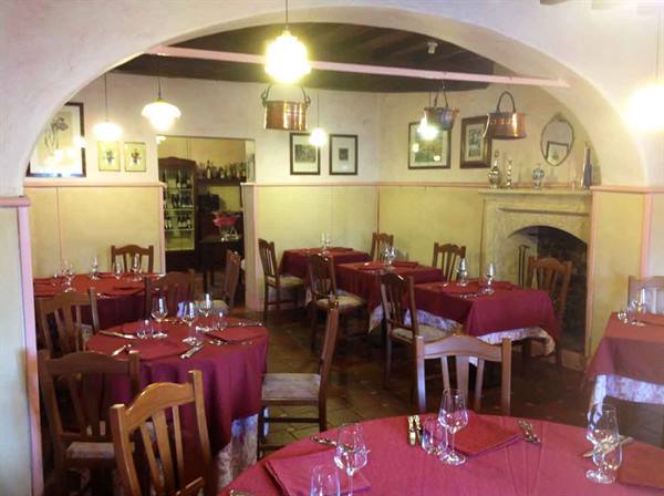 Trattoria dining room with red tablecloths, fireplace and hanging copper pots
