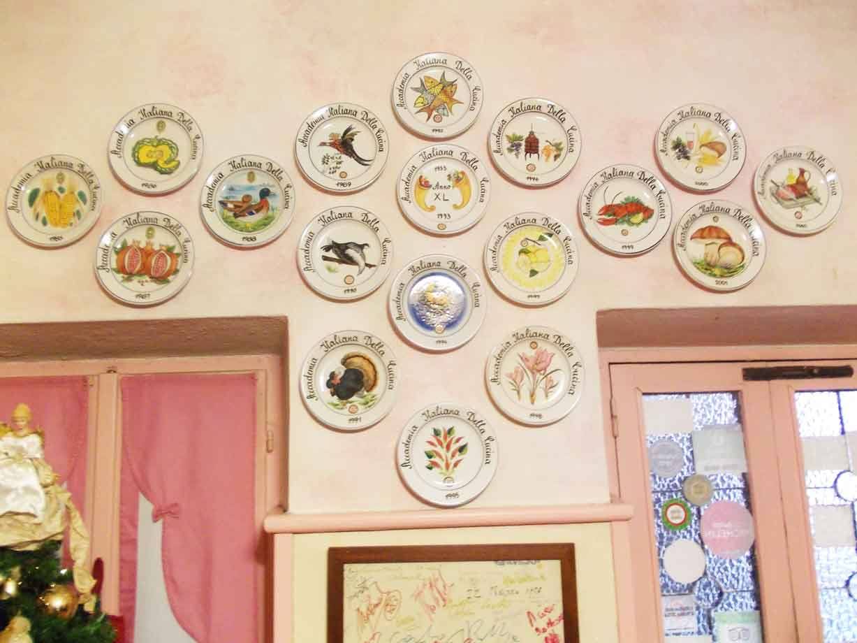 Parete rosa con piatti in ceramica decorati appesi, tende rosa e albero di Natale