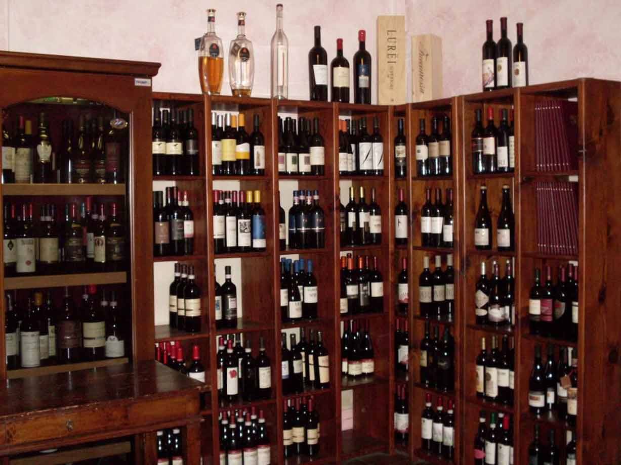 Cantina con scaffali in legno pieni di bottiglie di vino e liquori