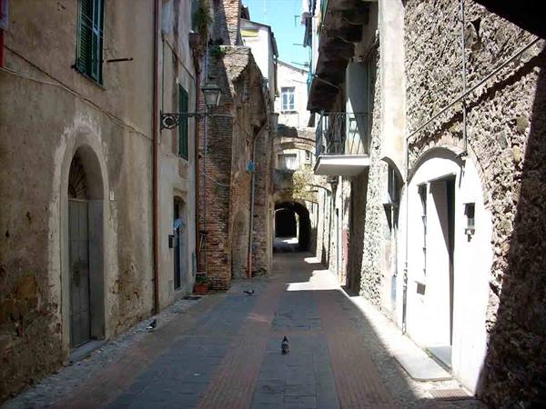 Medieval alley between stone houses, arches and sunlight