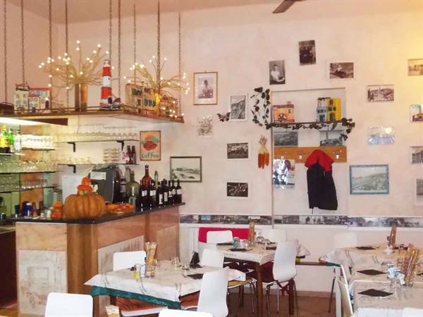 Trattoria dining room with marble counter, bottles, pumpkins, vintage photos on walls