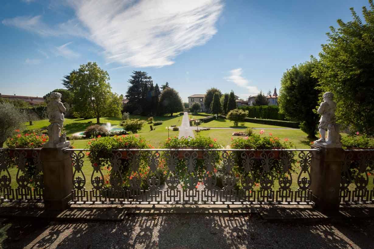 Balaustra in ghisa con statue e fiori sopra il giardino, cielo azzurro