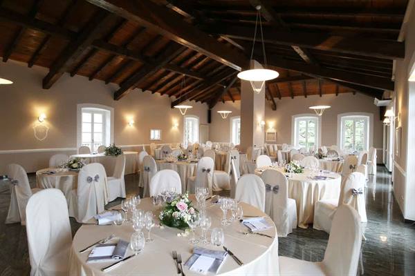 Wedding banquet hall with set round tables, wooden beamed ceiling