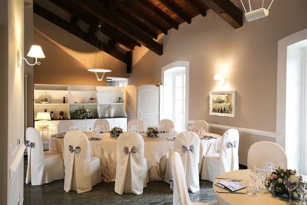Banquet hall with set tables, white chair covers and dark wooden beams