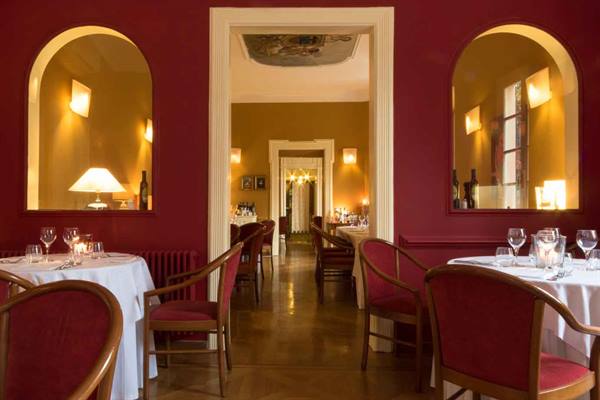 Dining room with burgundy walls, arched mirrors, set tables and warm light