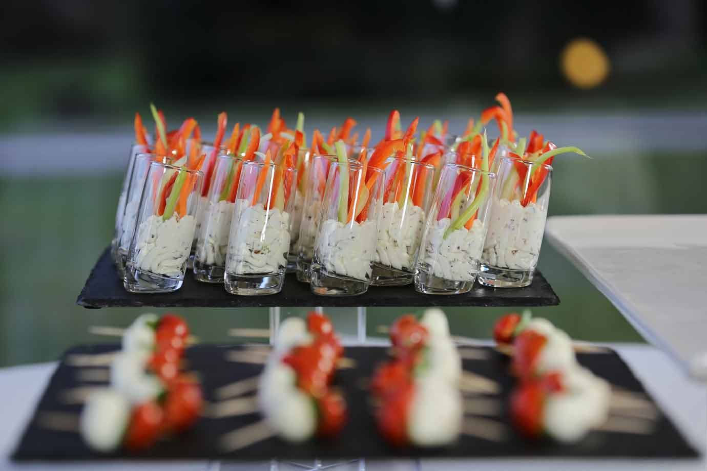 Bicchierini di vetro con formaggio spalmabile e bastoncini di peperone su ardesia nera