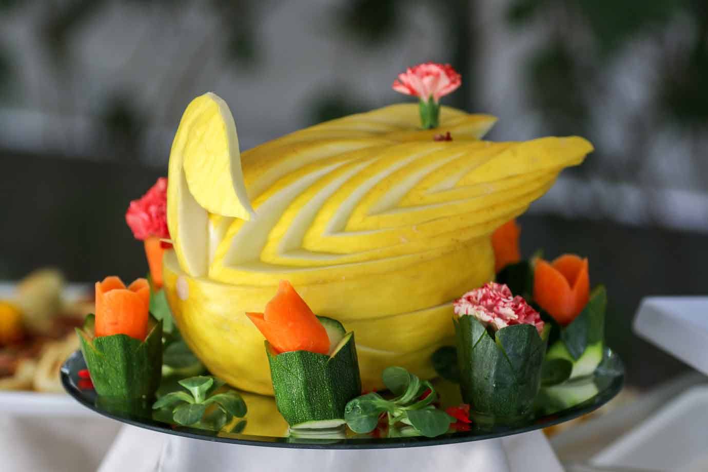 Melone intagliato a forma di cigno con fiori di zucchine e carote