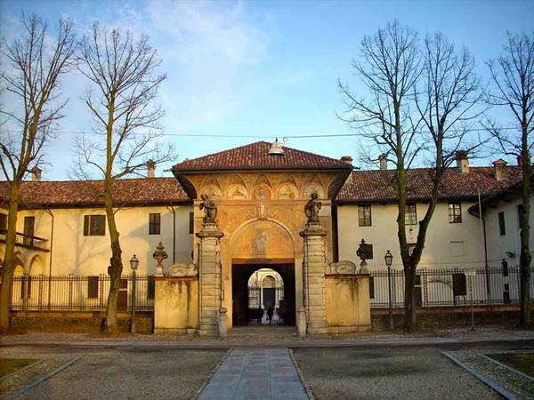 Frescoed entrance of the Certosa di Garegnano among bare trees, golden light