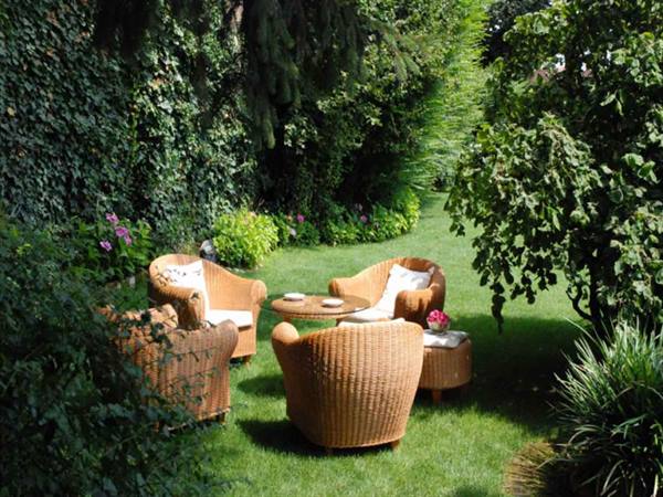 Wicker armchairs and round table on the green garden lawn