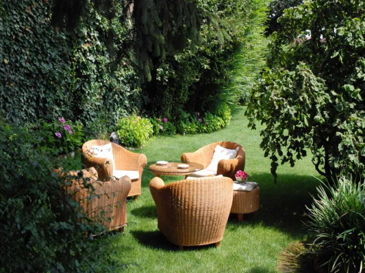Poltrone di vimini e tavolino rotondo sul prato verde del giardino