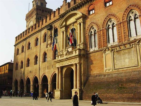 Palazzo d'Accursio in Bologna, red bricks, arcades and flags on the facade