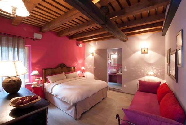 Hotel bedroom with pink walls, wooden beams and red sofa
