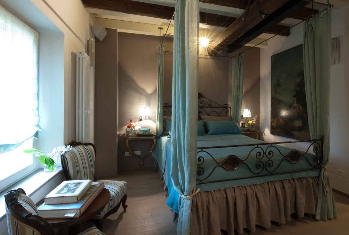 Camera con letto a baldacchino in ferro battuto e travi di legno a vista