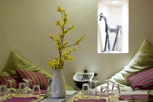 Set table with glasses and ceramics, yellow flowers, carved horse in the niche