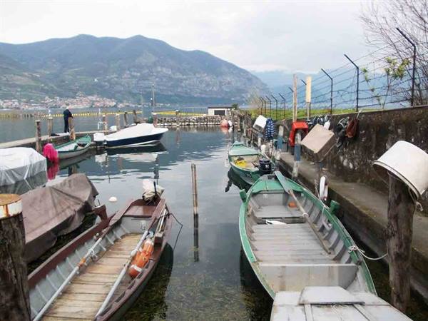 Wooden boats moored at the pier, Lake Iseo with mountains behind