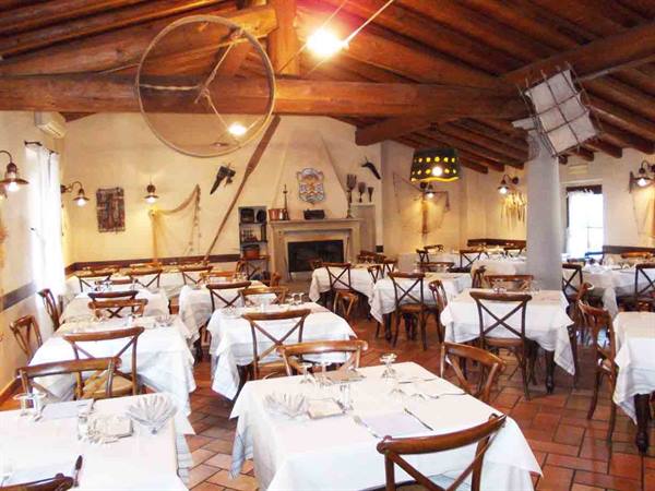Trattoria dining room with set tables, wooden beams and fireplace