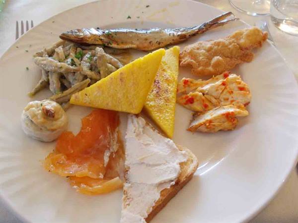 White plate with frittata, smoked salmon, bread, fried fish and pasta