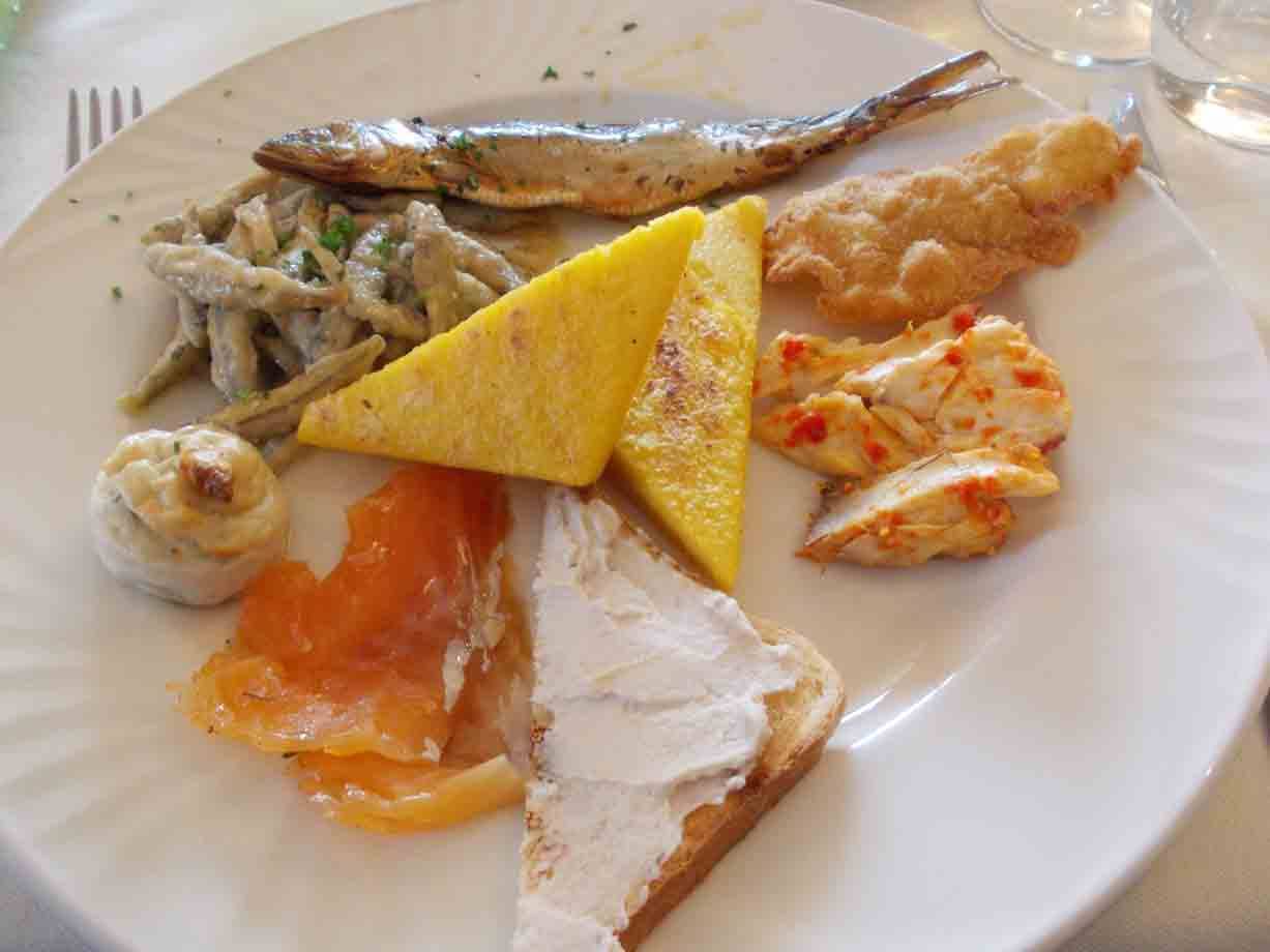 Piatto bianco con frittata, salmone affumicato, pane, pesce fritto e pasta