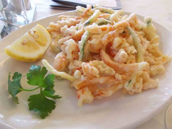 Batter-fried shrimp and zucchini on a white plate with lemon and parsley
