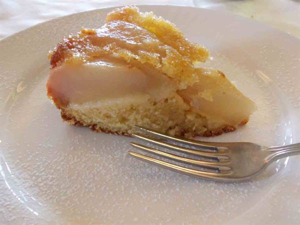 Slice of pear cake on white plate, silver fork, natural light