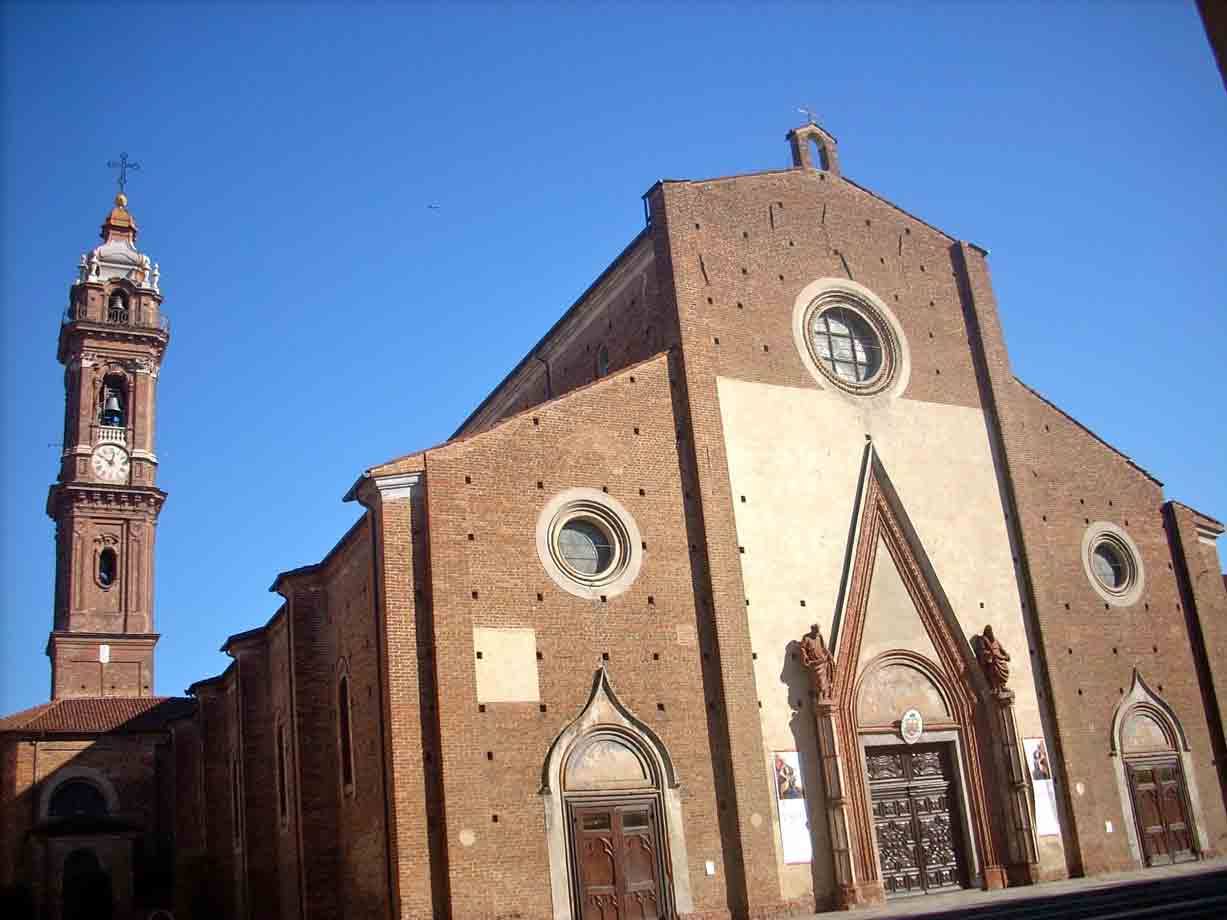 Facciata in mattoni della cattedrale di Saluzzo con campanile sotto cielo azzurro