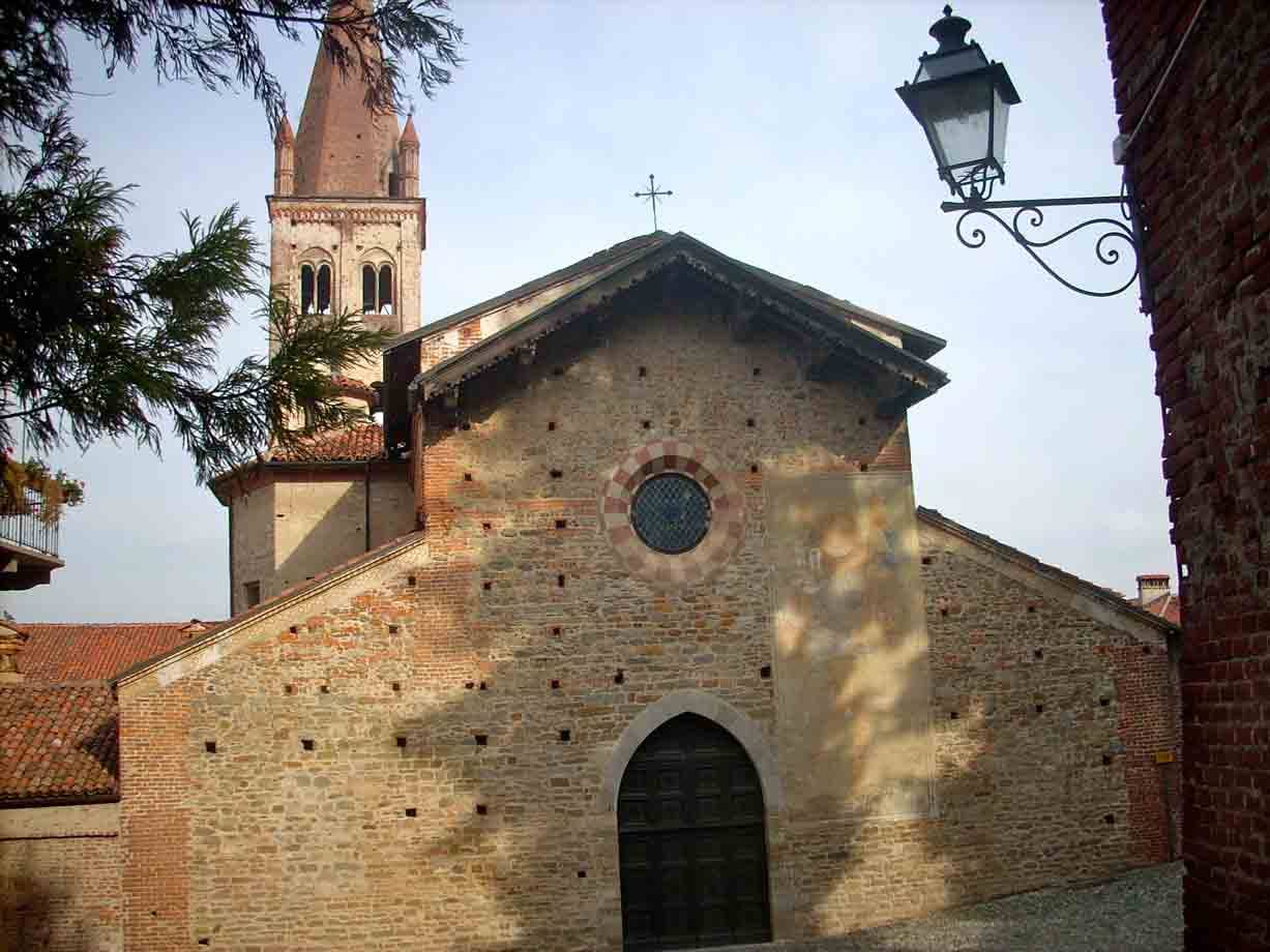Chiesa in pietra e laterizio con rosone e campanile, lampione in ferro battuto