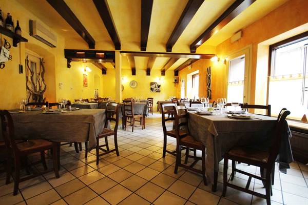 Trattoria dining room with set tables, wooden beams and yellow walls