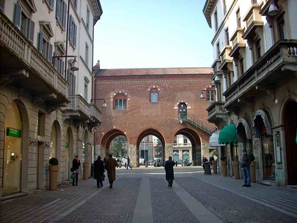 People walk toward the brick Arengario palace with arches, Monza