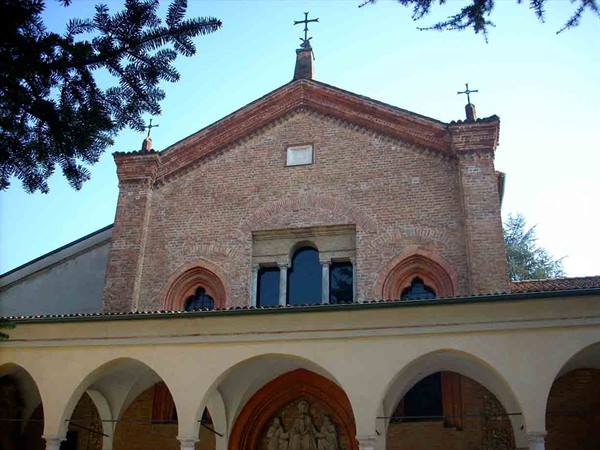 Brick church facade with crosses and arched stone portico under blue sky