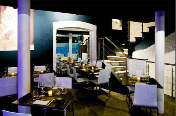 Restaurant dining room with set tables, lit candles, stone staircase and white columns