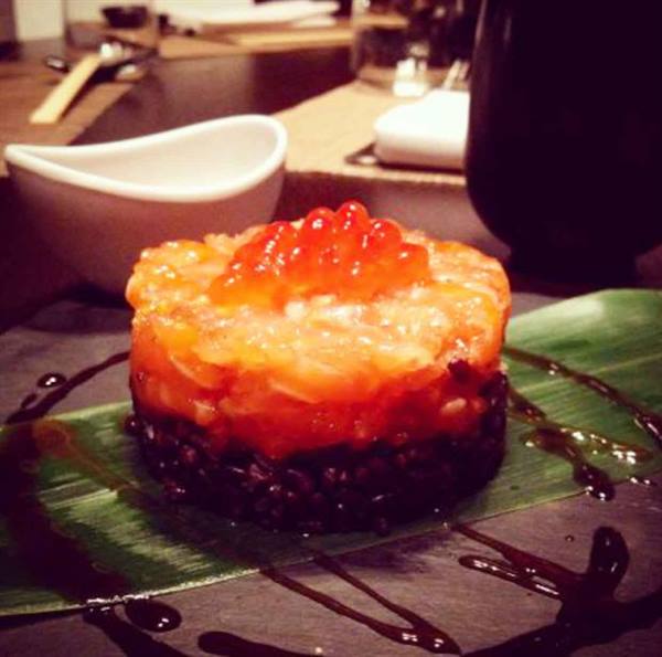 Salmon tartare on black rice, salmon roe, green leaf, dark sauce drizzle