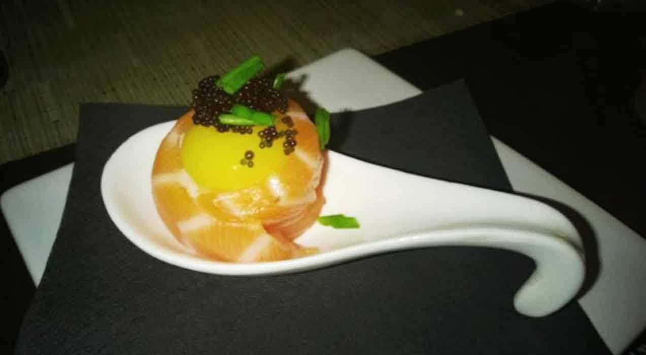 Salmone affumicato con tuorlo e caviale su cucchiaino di ceramica bianca