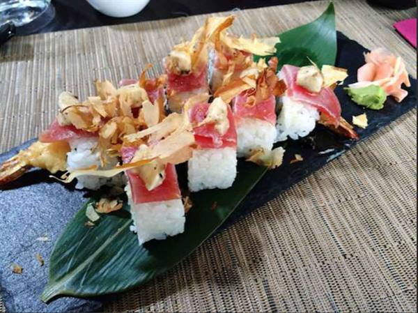 Tuna sushi pieces on a green leaf, served on a black slate in the restaurant