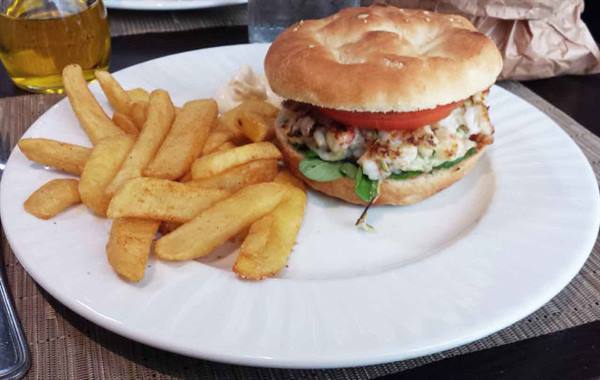 Chicken sandwich with tomato and arugula on white plate with fries