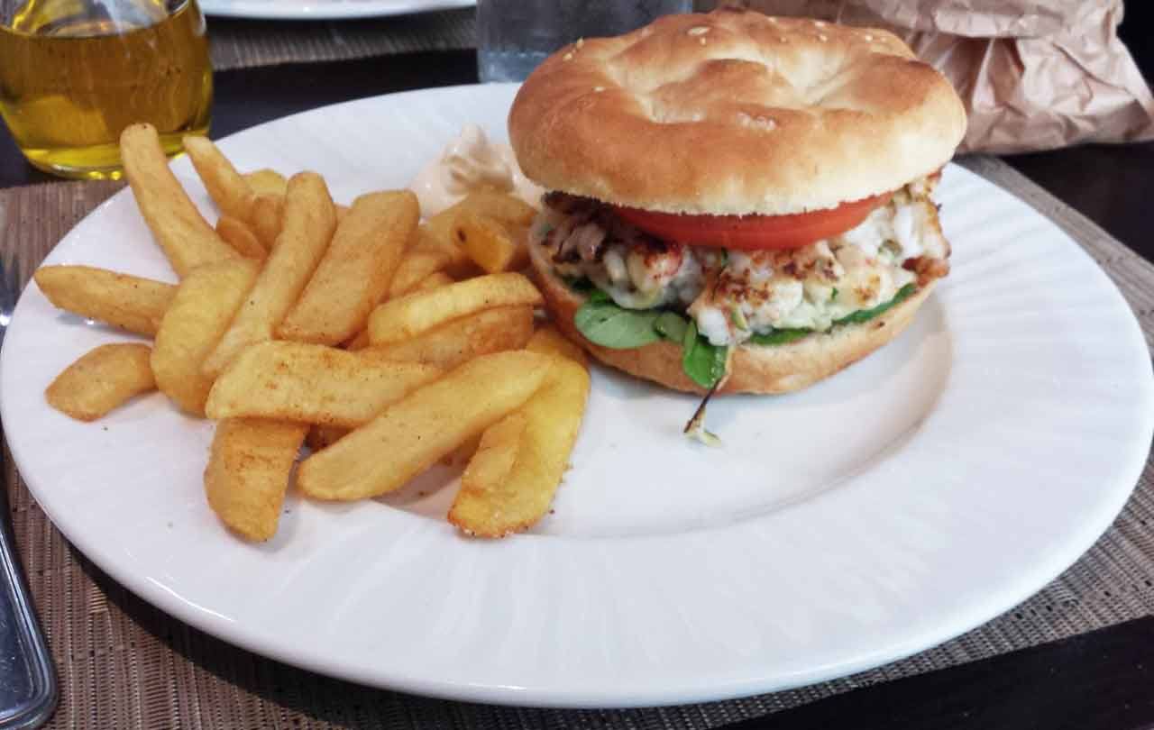 Panino con pollo, pomodoro e rucola nel piatto bianco con patatine fritte