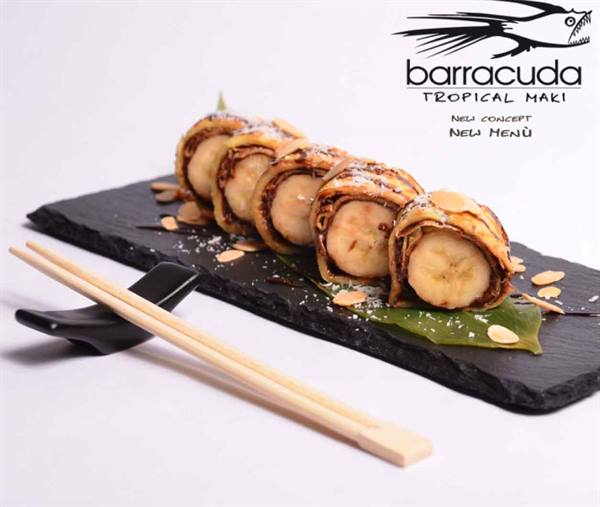 Tropical sushi rolls with banana and chocolate on black slate board