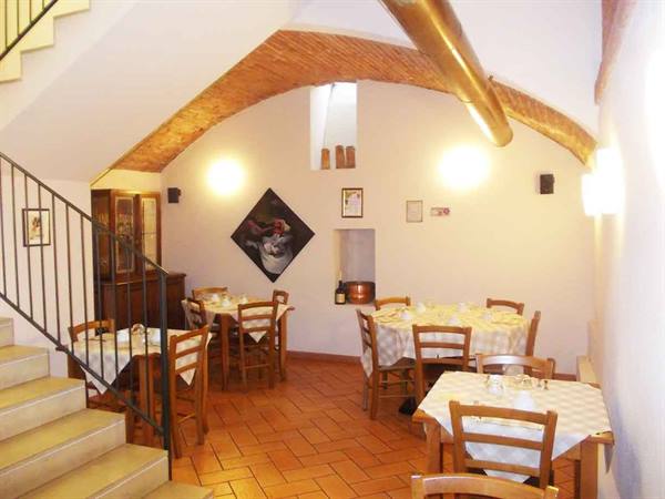Trattoria dining room with set tables, brick vault and terracotta floor