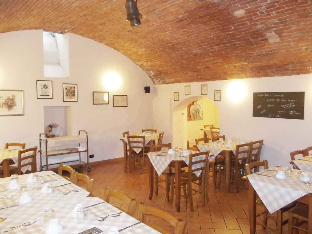 Sala da pranzo con tavoli apparecchiati, soffitto a volta di mattoni e seggioline in legno