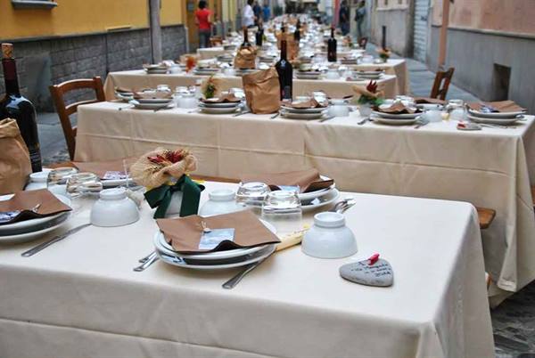 Long tables set with dishes and wine bottles in a narrow alley