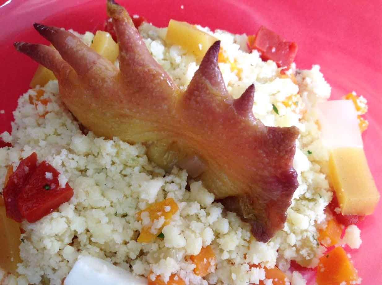 Zampa di pollo arrosto su couscous con verdure, piatto rosa in luce naturale