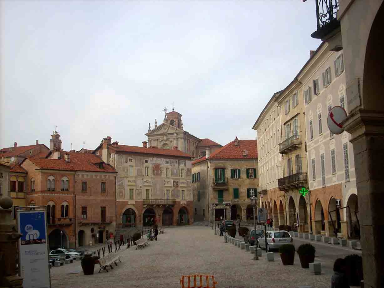 Piazza Maggiore di Mondovì: palazzi affrescati con portici, chiesa barocca, ciottolato sotto cielo grigio