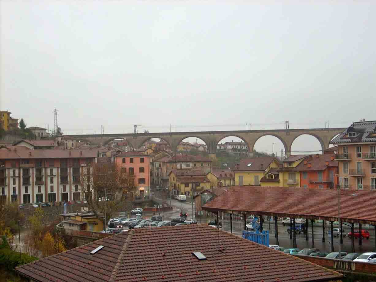 Viadotto ferroviario in muratura con grandi archi sopra le case dal tetto rosso