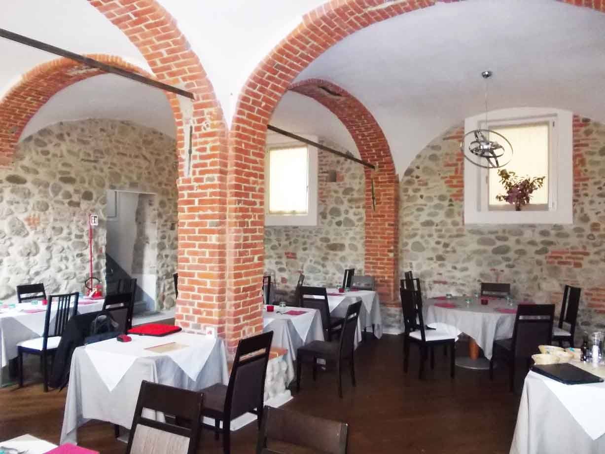 Sala da pranzo con volte in mattoni rossi e muri di pietra, tavoli apparecchiati