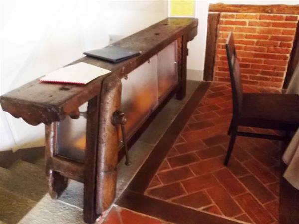 Antique wooden workbench repurposed indoors, terracotta brick floor, wooden chair