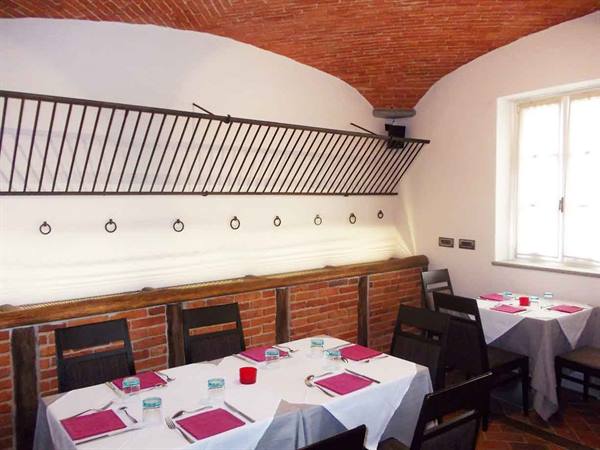 Restaurant dining room with red brick vault, tables set with white tablecloths and fuchsia napkins