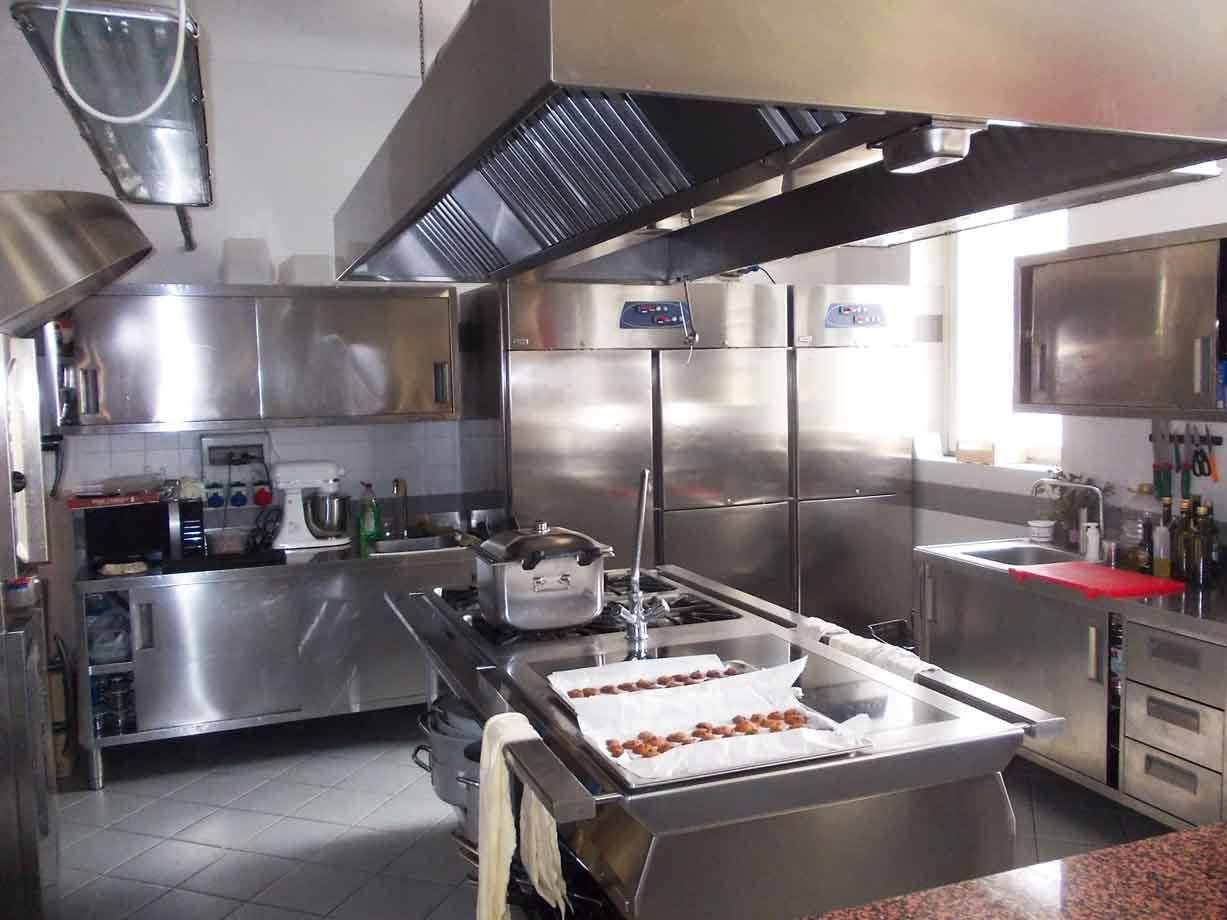 Cucina professionale in acciaio inox, cappa, frigoriferi e dolcetti nel vassoio