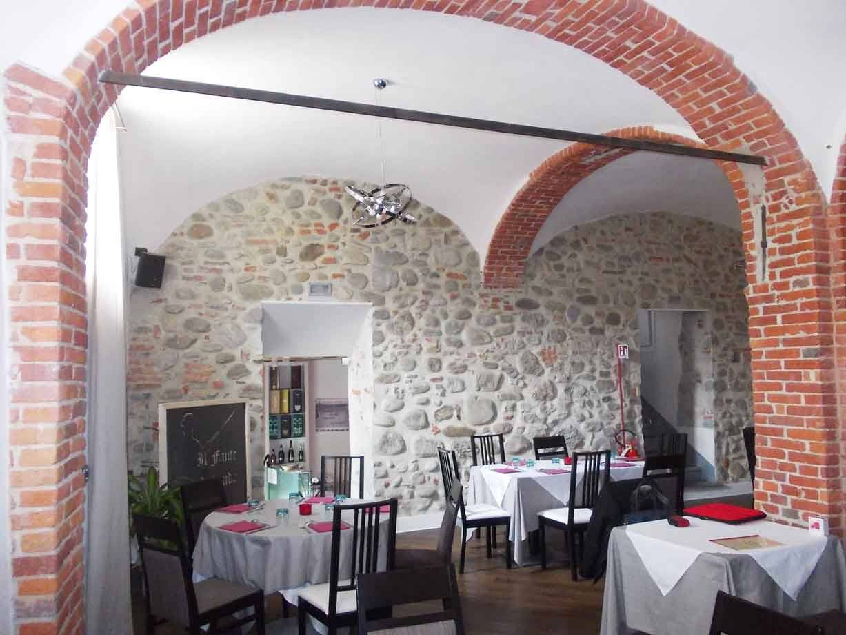 Sala di ristorante con archi in mattoni rossi e muri di pietra a vista
