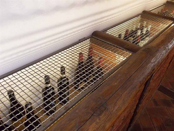Wine bottles behind metal grid on rustic wooden counter, warm light