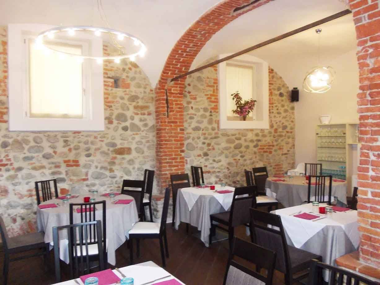 Sala di ristorante con volte in mattoni, pareti in pietra e tavoli apparecchiati