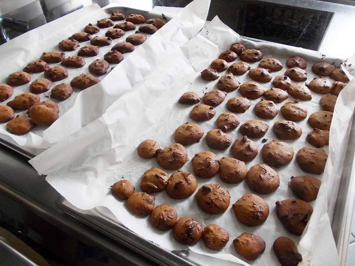 Dolcetti appena sfornati su teglie con carta forno, cucina domestica